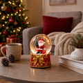 Glob de Zăpadă Premium de Crăciun cu Moș Crăciun, Bază tip Cutie Cadou cu Fundă Aurie, Muzică, Lumină LED și Efect de Ninsoare – 15 × 10 cm